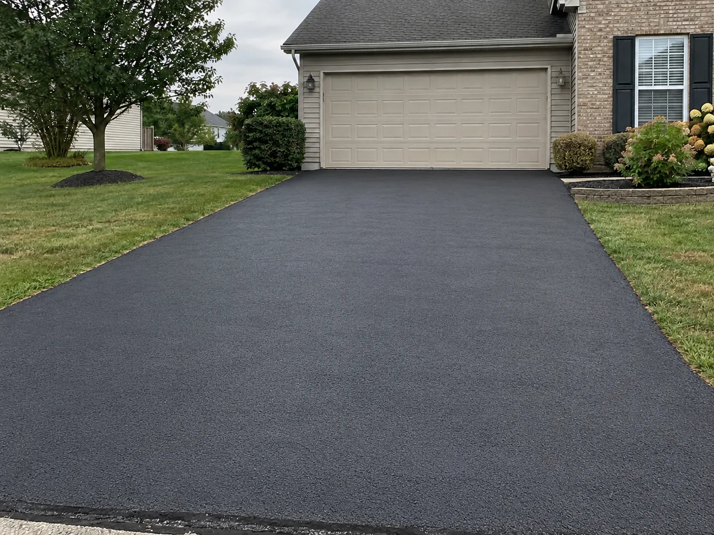 After: a freshly sealcoated driveway, deep black and finished